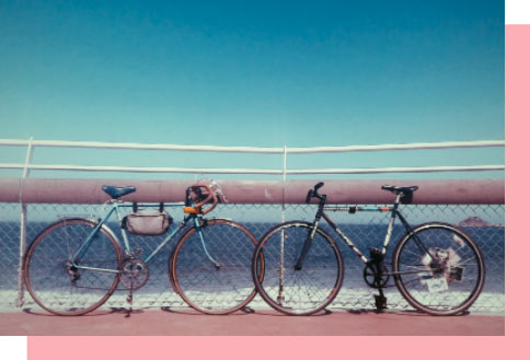2 bikes by the sea on a sunny day.