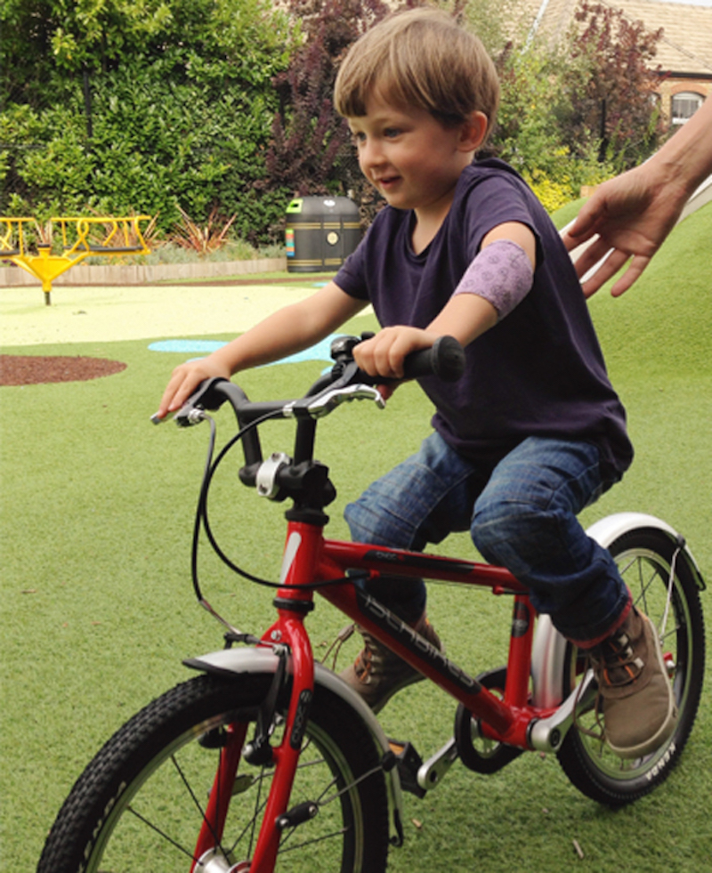 little boy riding a red bike birthday patchwork present from his friends