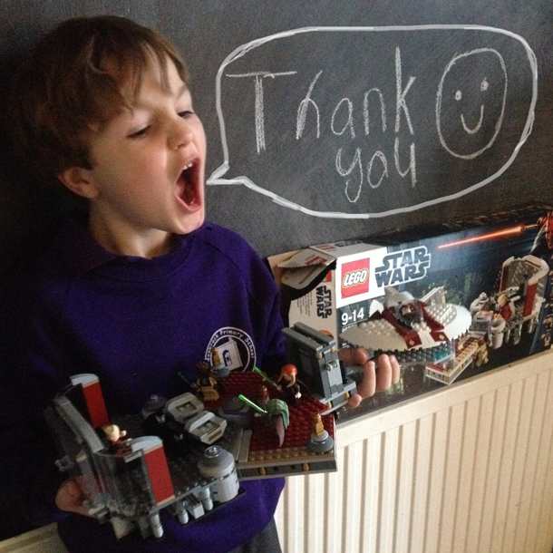 boy holding birthday gift Lego set thank you speech bubble