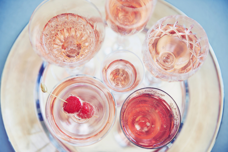 Overhead of vintage glasses with pink rosé champagne on a silver tray