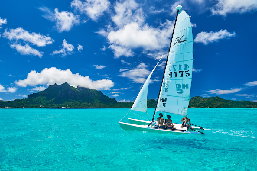 Couple sailing on turquoise sea around the Islands of Bora Bora
