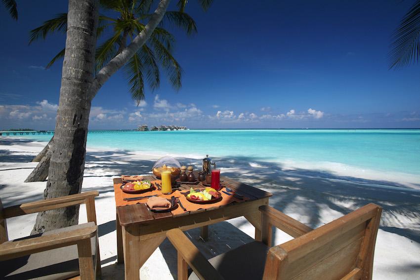 Table set for breakfast on beach, overlooking turquoise ocean, The Maldives