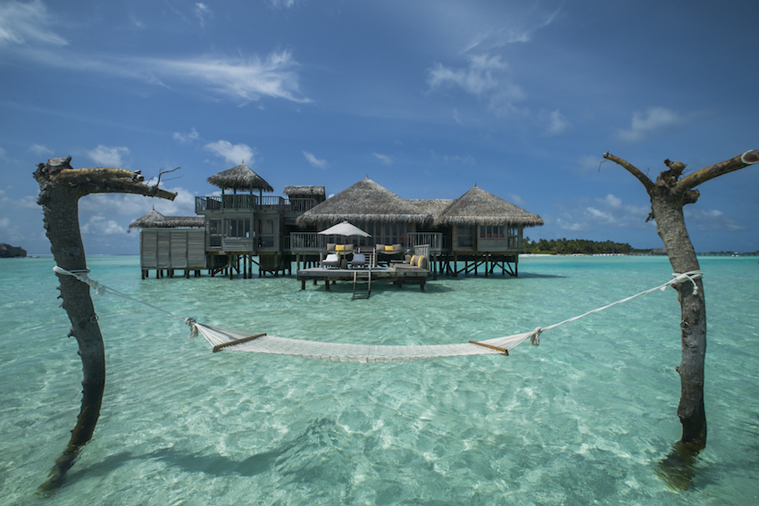 Hammock over water with over water villas in background, The Maldives