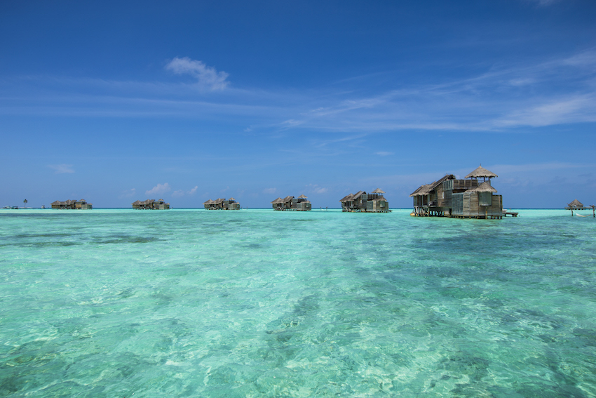 View looking across shallow turquoise water to over water villas, the Maldives