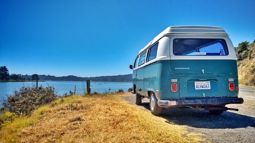 Blue Campervan parked beside water