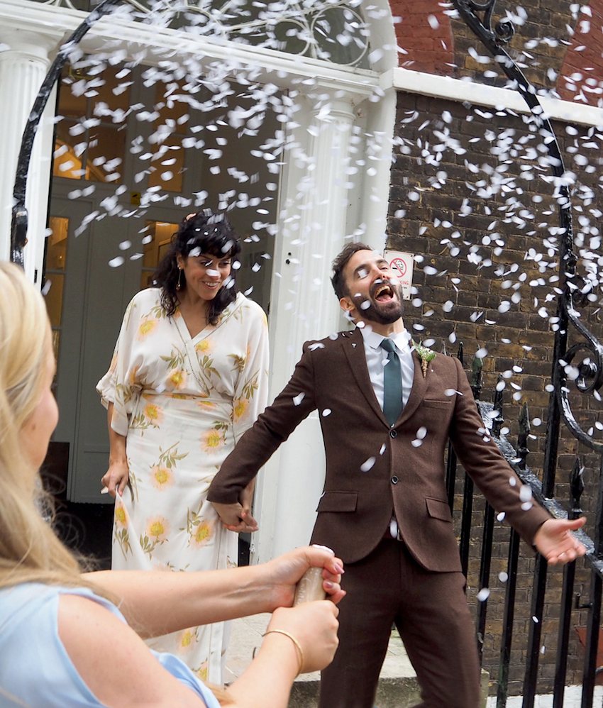 Couple on wedding day walking out of ceremony in shower of confetti