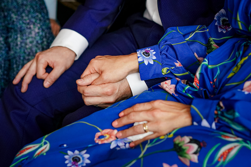 Couple on wedding day holding hands. Bride and Groom wearing blue