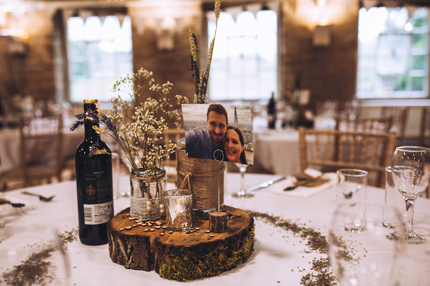 Wedding breakfast tables set with natural decor, logs and tea lights