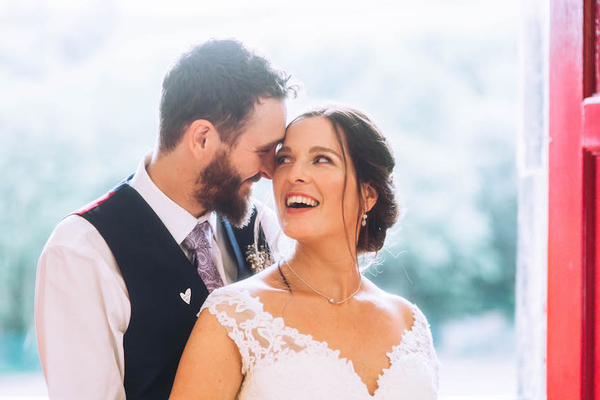 Close up portrait of bride and groom smiling at each other in doorway in sunshine