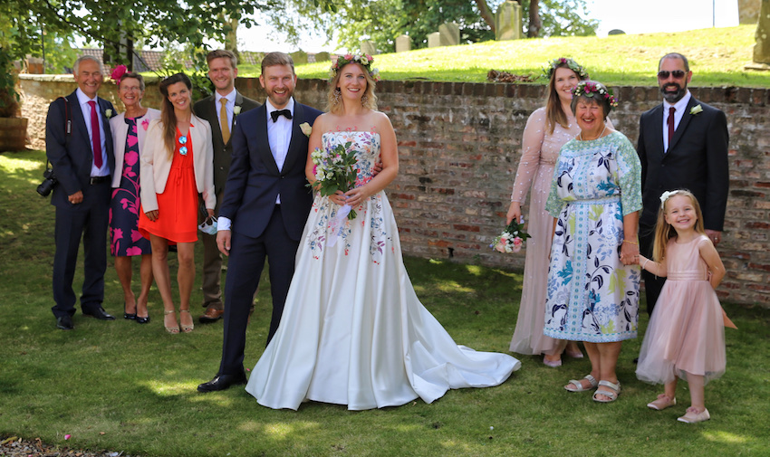 Group wedding shot, bride and groom with families socially distancing on either side