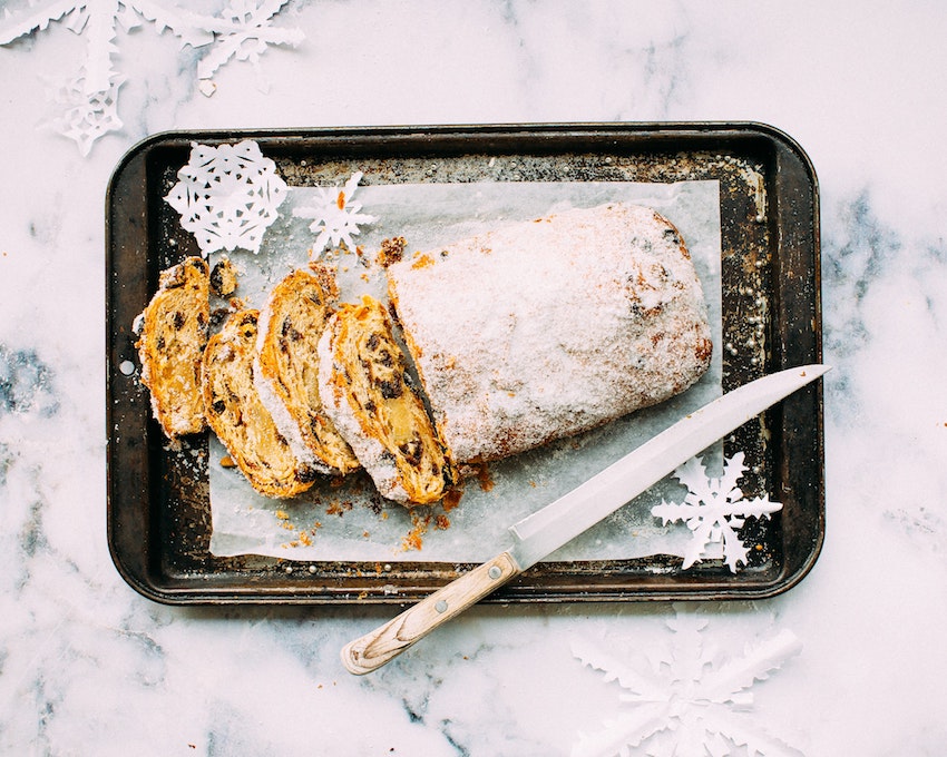 Christmas stollen loaf on a baking tray with knife placed on side
