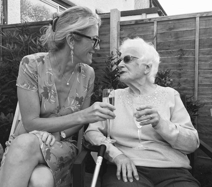 Grandmother and granddaughter enjoying a glass of champagne in garden