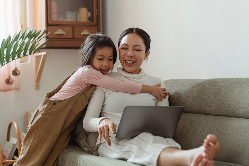 Mother and daughter on laptop setting up virtual school Christmas fair